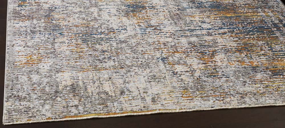 Close-up of a textured area rug with an intricate pattern blending hues of gray, cream, blue, and gold, creating a sophisticated and contemporary floor covering suitable for modern interior designs.